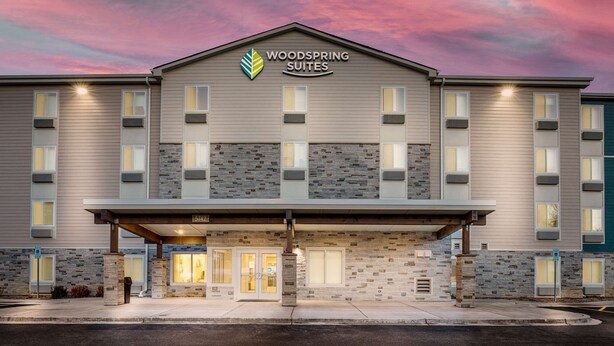 Um hotel com fachada de pedra, entrada coberta e uma placa com a inscrição "WOODSPRING SUITES".