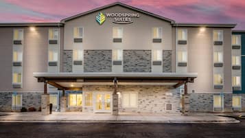 A multi-story hotel with a stone facade, a covered entrance, and a sign reading 'WOODS SPRING SUITES'.