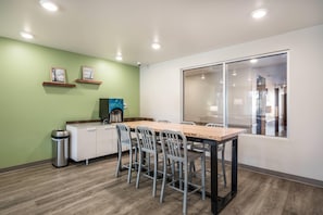 A modern kitchen with a dining area, equipped with a coffee machine, a trash bin, and a window with a view. - WoodSpring Suites Gurnee - Chicago (Gurnee)