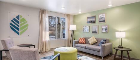 A modern living room with a sofa, chairs, a coffee table, and a floor lamp.