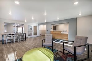 A modern interior with a reception desk, a dining area with chairs, and a reception desk with a computer. - WoodSpring Suites Gurnee - Chicago (Gurnee)