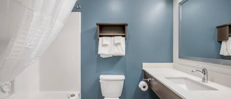 A bathroom with a toilet, a sink, a mirror, and a shower curtain.
