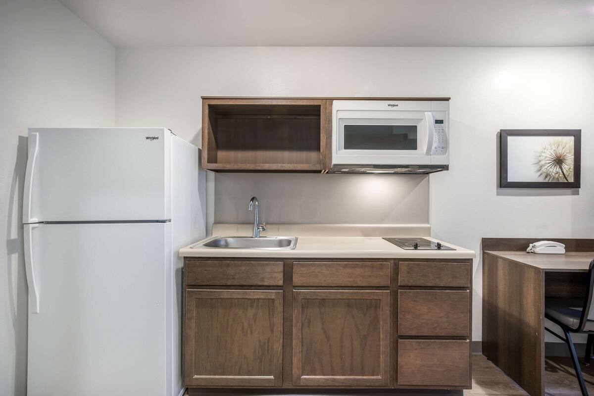 A compact kitchen with a white refrigerator, a microwave, and wooden cabinets.