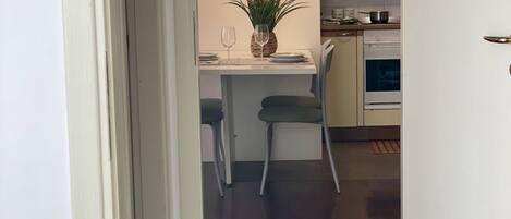 Una cocina compacta con comedor, una planta en maceta y un reloj en la pared.