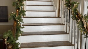 A staircase with white railings and wooden steps, decorated with greenery and lights.