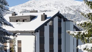 Een modern gebouw met een witte gevel, grote ramen en een schuin dak.