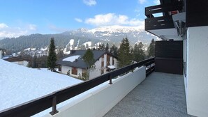 Een balkon met uitzicht op besneeuwde bergen en een stad.