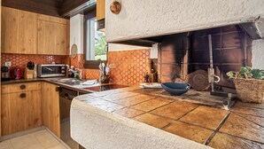Een keuken met houten kastjes, een magnetron, een spoelbak en een groot raam.