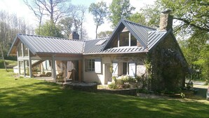 Een modern huis met een stenen gevel, grote ramen en een schuin metalen dak.
