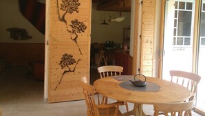 Een eetgedeelte met een houten tafel en stoelen, een leren bank en een houten deur met een ontwerp van een boom.