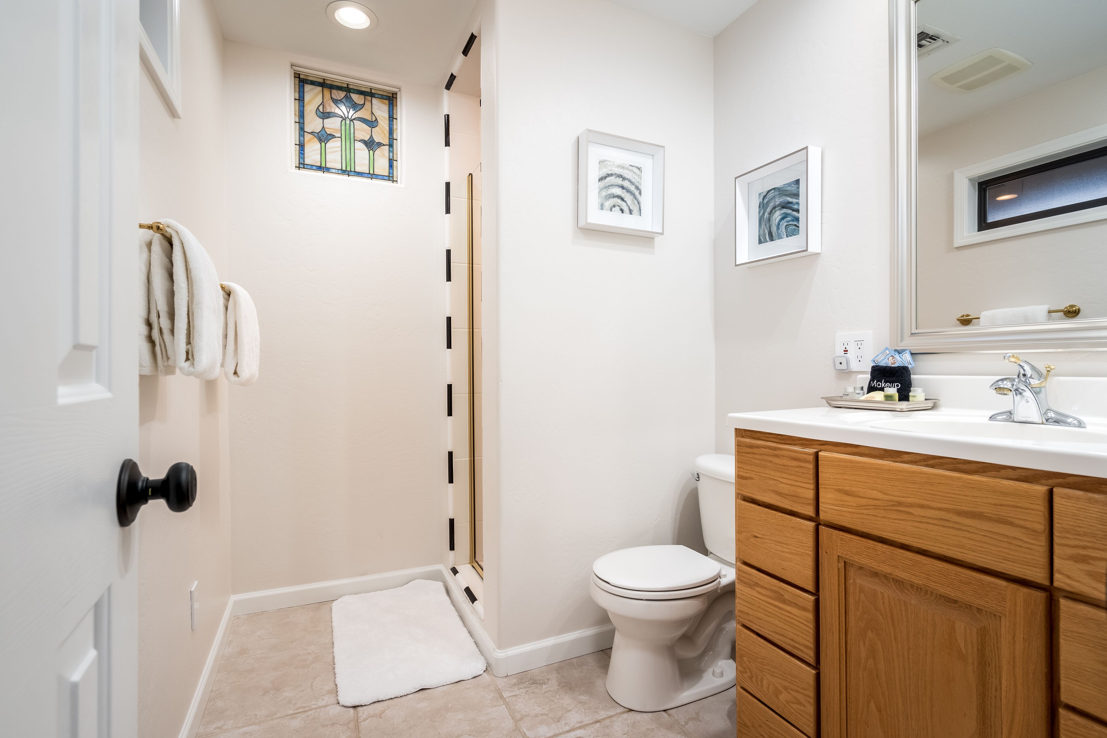 A bathroom with a white toilet, a sink with a mirror, and a shower area.