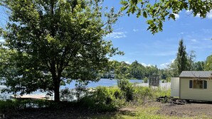 A lakeside property with a small cabin, a large tree, and a grassy area. - Berkshire Lake at the Pillow, and EV! (Otis)