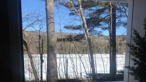 A view from a door into a snowy outdoor area with a wooden deck and a railing. - Berkshire Lake at the Pillow, and EV! (Otis)