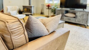 A living room with a sofa, a television, and a fireplace. - Spacious Fly Creek Retreat – Game Rm, Creek Views & Minutes to Cooperstown & DP (Fly Creek)