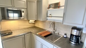 A compact kitchen with a microwave, coffee maker, and a sink. - Garden Patio Studio near Bosque, Old Town (Albuquerque)