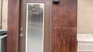 A brown door with a window, a small wall-mounted light, and a textured wall. - Garden Patio Studio near Bosque, Old Town (Albuquerque)