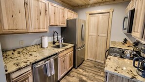 Una cocina con armarios de madera, encimeras de granito y electrodomésticos de acero inoxidable, además de un microondas.