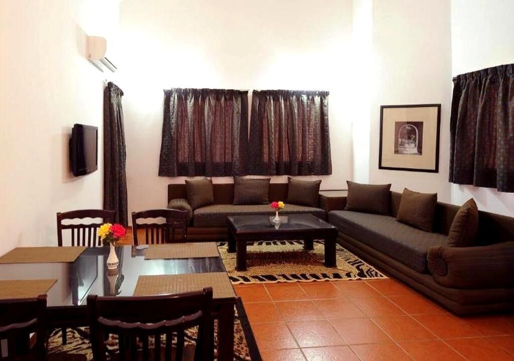 A living room with a sofa, chairs, a coffee table, and a TV.