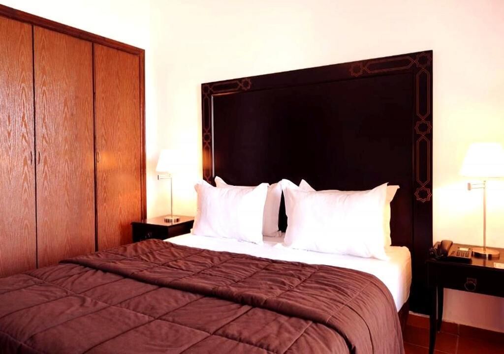 Een hotelkamer met een groot bed, twee nachtkastjes en een houten garderobe.