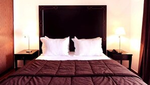 Una habitación de hotel con una cama grande, dos mesitas de noche y dos lámparas.