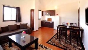 Ein Wohnzimmer mit Sofa, Couchtisch und Essbereich mit Stühlen und Tisch.