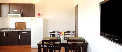 A compact living space with a dining area, kitchen, and a mounted TV.