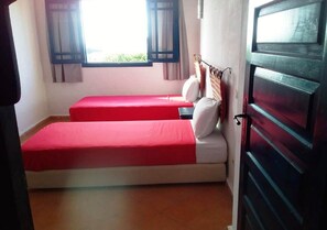 A room with two beds, a window with curtains, and a door.