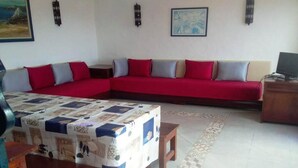 Ein Wohnzimmer mit einem roten Sofa, einem Holztisch und einem gemusterten Teppich.