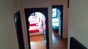 Ein Flur, der zu einem Zimmer mit einem Bett und einem Fenster führt.