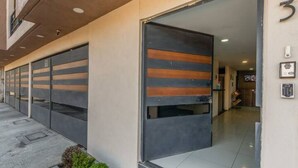A modern building entrance with a large sliding door, a small garden area, and a clean tiled floor. - Suite Premium Increíble! A 2 Minutos DEL Tec! S06 (Ciudad López Mateos)