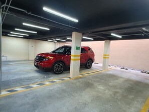 En parkeringskælder med en rød SUV parkeret tæt på en søjle med pile.