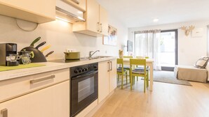 Una cocina compacta con estufa, lavamanos y comedor con mesa y sillas.