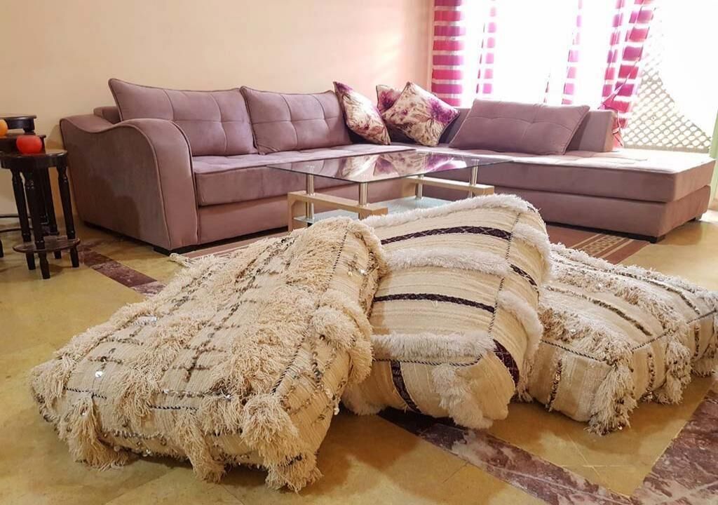 Una sala de estar con un sofá, una mesa de centro de vidrio y un tapete decorativo.