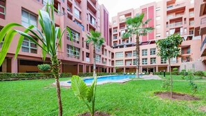 A courtyard with a swimming pool, surrounded by a multi-story building with balconies. - Superb apartment in Marrakech 4582 (Marrakech)