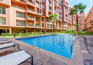 A swimming pool surrounded by a multi-story building with balconies. - Exceptional Apartment in Marrakesh 4582 (Marrakech)
