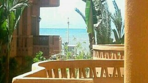 Une vue depuis un balcon doté d’une balustrade, donnant sur une étendue d’eau et des palmiers.
