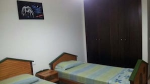 A bedroom with two single beds, wooden headboards, a nightstand, and a dark wardrobe. - Very nice apartment El Waha Saidia 4597 (Saidia)