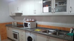 A kitchen with white cabinets, a microwave, a washing machine, and a sink. - Very nice apartment El Waha Saidia 4597 (Saidia)