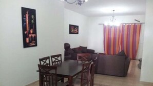 A dining area with a table and chairs, a sofa, and a colorful curtain. - Very nice apartment El Waha Saidia 4597 (Saidia)