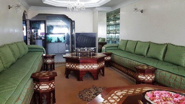 Ein Wohnzimmer mit grünen Sofas, einem Fernseher und einem dekorativen Couchtisch.