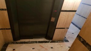 Ein Aufzug mit einer schwarzen Tür, Marmorböden und Holzvertäfelung an den Wänden.