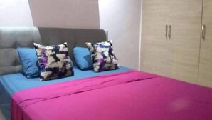 Un dormitorio con cama, dos almohadas, un armario y una mesita de noche.