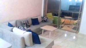 Una sala de estar con sofá, mesa de centro y puerta corrediza de vidrio que da a un área exterior.