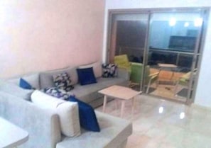 Ein Wohnzimmer mit einer Couch, einem Couchtisch und einer Schiebetür zu einem Außenbereich.