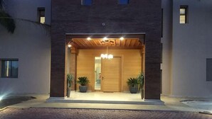 A modern building with a wooden facade, a central entrance with a door, and potted plants on either side. - Luxury villa in Marrakech 4613 (Marrakech)