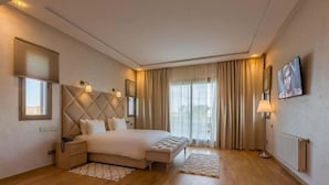 A modern hotel room with a large bed, a bedside table, a lamp, and a view of the city through the window. - Luxury villa in Marrakech 4613 (Marrakech)