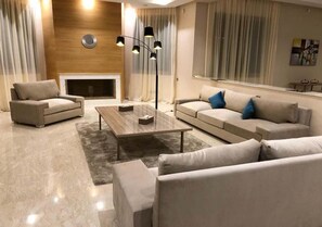 A modern living room with a fireplace, two sofas, a coffee table, and a floor lamp. - Luxury villa in Marrakech 4613 (Marrakech)