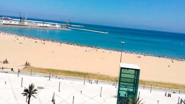Ein Strand mit freiem Blick auf das Meer und einem Steg im Hintergrund.
