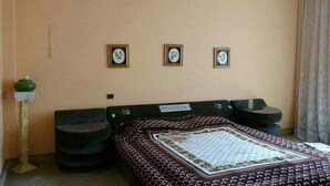 Ein Schlafzimmer mit einem Bett, zwei Nachttischen, einer grünen Vase und drei gerahmten Bildern an der Wand.