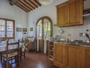 A kitchen with wooden cabinets, a tiled backsplash, a sink, and a dining area with a table and chairs.